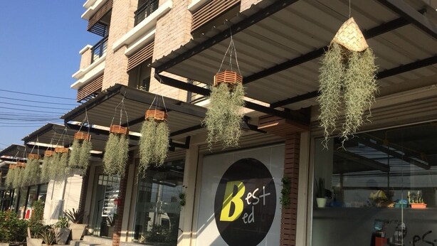 Un bâtiment orné de jardinières suspendues et sur lequel est apposée une grande enseigne portant le logo « Best ».