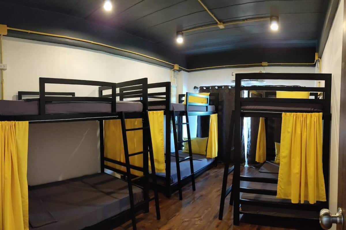Une chambre de dortoir avec des lits superposés, des meubles en bois et des rideaux jaunes.