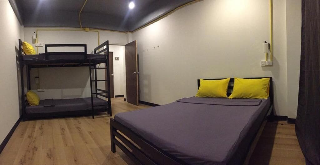 Une chambre avec des lits superposés, un lit simple et un plancher en bois.