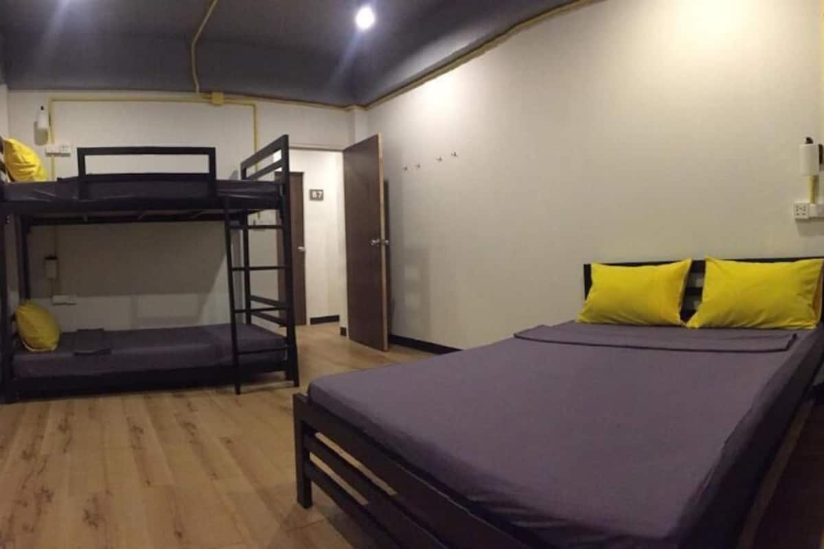 Een kamer met stapelbedden, een enkel bed en een houten vloer.