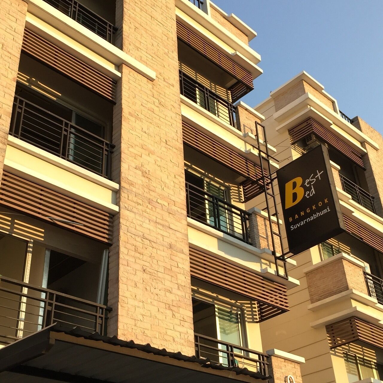 A multi-story building with a sign indicating it is a hotel named "Best Bed Bangkok Suvarnabhumi".