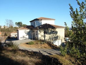 Uma casa de dois andares com telhado de telhas, garagem e entrada por um caminho.