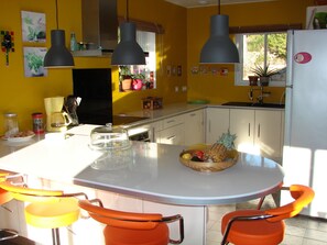 Uma cozinha com ilha central, cadeiras laranja e uma geladeira.