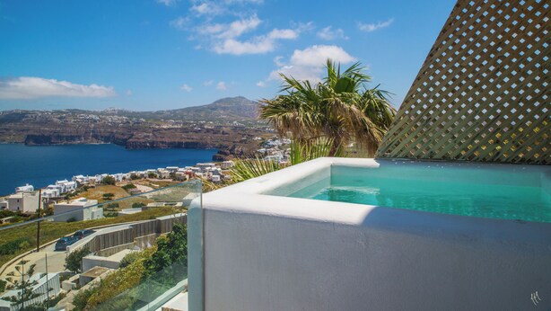 Una piscina con vistas despejadas a un pueblo costero y una montaña al fondo.