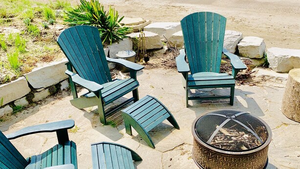 A beachside seating area with Adirondack chairs and a fire pit.
