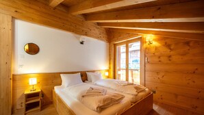 Ein Schlafzimmer in einer Holzhütte mit einem Bett, Nachttischlampen und einem kleinen Holzschemel.