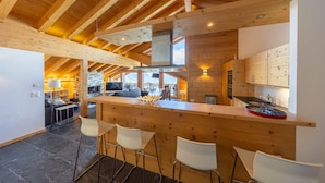 Eine moderne Küche mit einer Holztresorecke, Steinböden und Blick auf den Essbereich.
