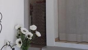 A staircase leading to a landing with a white door, a black metal chair, and a vase with white flowers.