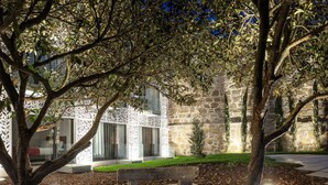 A courtyard with a stone wall, a glass door entrance, and a bench. - Caléway Hotel (Vila Nova de Gaia)