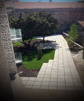 Un sendero pavimentado que conduce a un muro de piedra con un árbol en el centro.