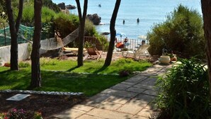 Een terras met een hangmat, zitplaatsen buiten en uitzicht op zee.