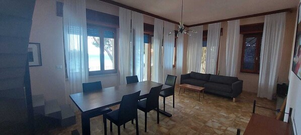 A room with a dining table, chairs, a sofa, and a small coffee table.