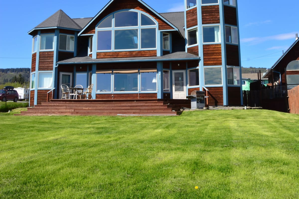 A large, multi-story house with a prominent tower and a wrap-around porch.