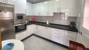 A modern kitchen with white cabinets, a black countertop, stainless steel appliances, and a tiled floor. - Sleeps 8 | Villa Pinomar | CG R865 (Nerja)
