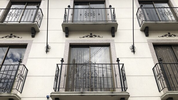 A building facade with multiple balconies, each with ornate metal railings and windows with shutters. - Hotel Bogota Inn Parkway (Bogotá)