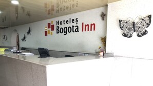 A reception desk at the Hoteles Bogota Inn with a sign above it, a telephone, a notepad, and a small plant. - Hotel Bogota Inn Parkway (Bogotá)
