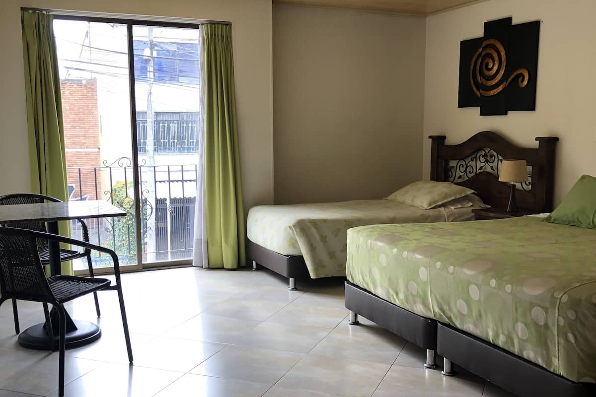 Habitación de hotel con dos camas, una mesa y una silla.