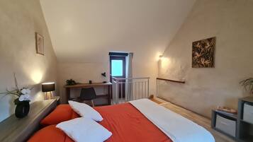 Un dormitorio con cama, escritorio, silla y ventana.