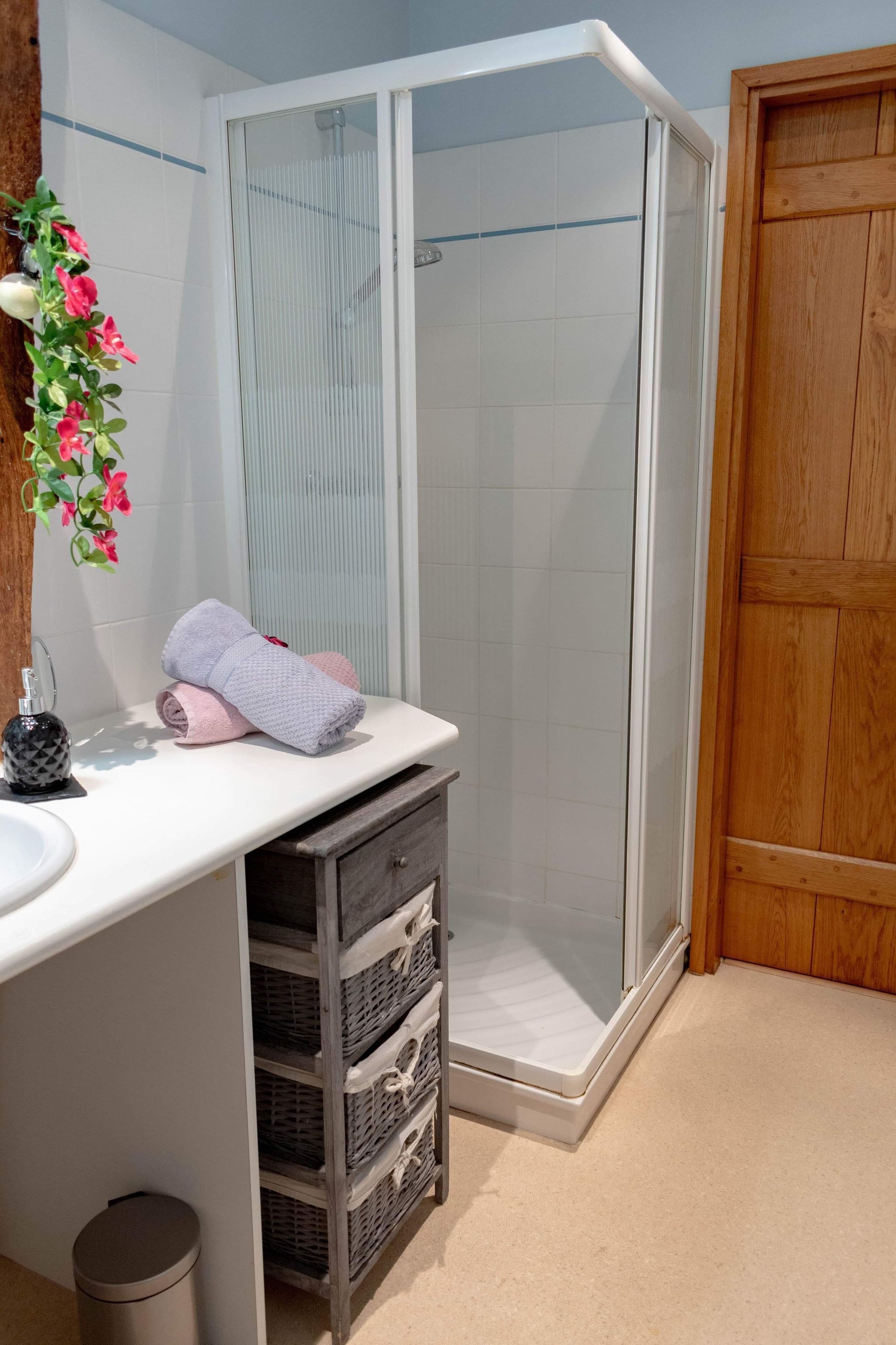 A bathroom with a shower, a sink, and a wooden door.