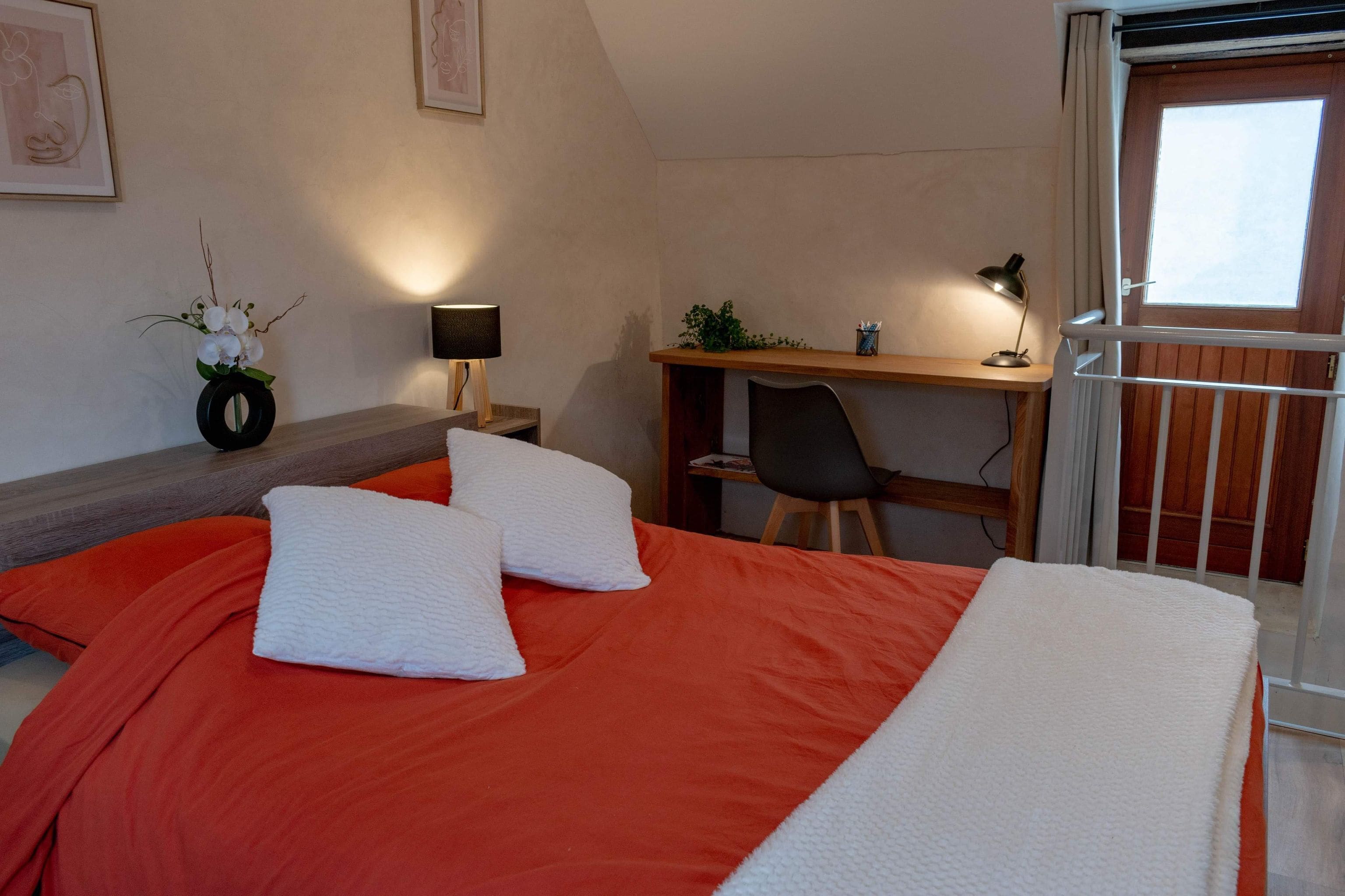 A bedroom with a bed, a desk, and a chair.