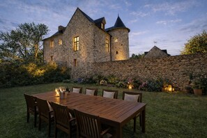 A stone castle with a wooden table and chairs in the garden. - Manoir De La Coudre (Change)