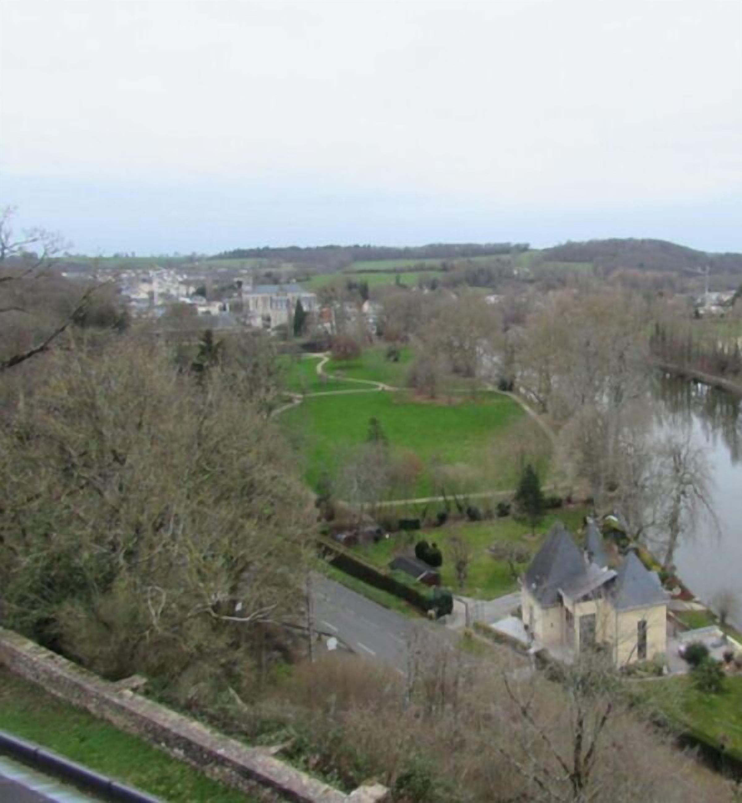 A riverside view of a town with a prominent church and residential buildings.