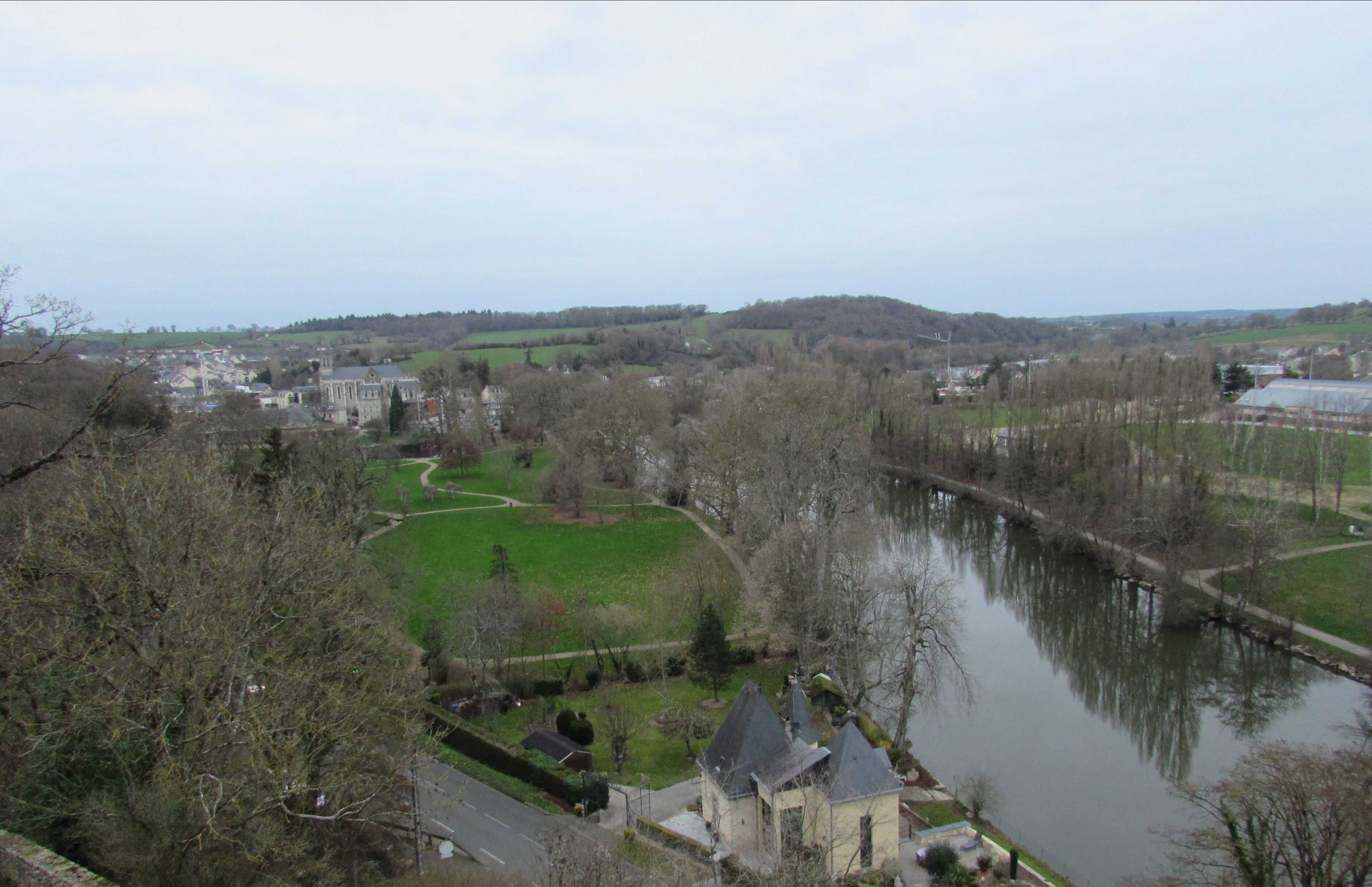 Vista de un río con un pueblo, una iglesia destacada, un puente y vegetación circundante.