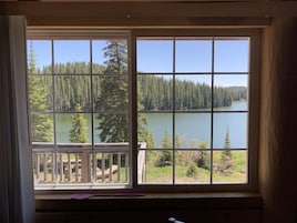Una habitación con un ventanal que ofrece vistas a un lago rodeado de árboles.