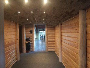 A corridor with wooden walls and a carpeted floor, leading to a reception area with a sign that reads "Welcome". - Alexander lake lodge (Cedaredge)