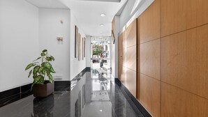 A polished hallway with a potted plant, wooden paneling, and framed artwork on the walls.