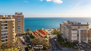 A coastal view with buildings, a parking lot, and a clear sky.