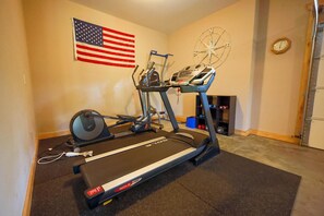 Ein Heimfitnessraum mit Laufband, Ergometer und Gewichten.