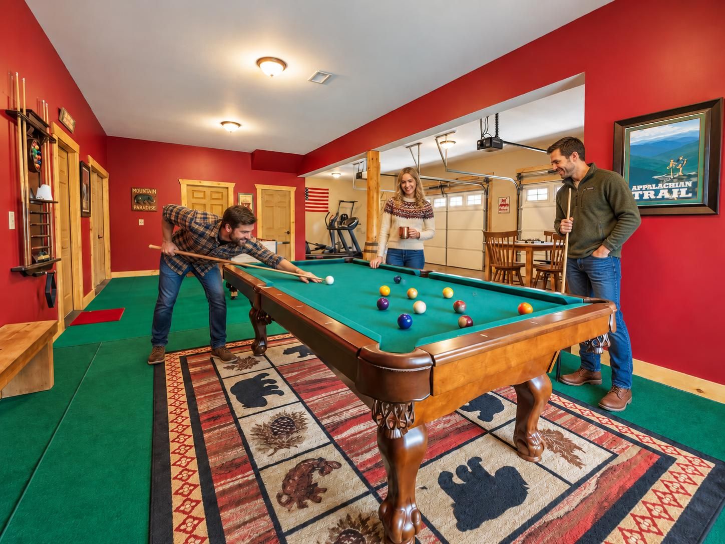 A pool table in a room with red walls, a patterned carpet, and a framed picture of the Appalachian Trail.