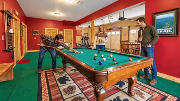 A pool table in a room with red walls, a patterned carpet, and a framed picture of the Appalachian Trail.