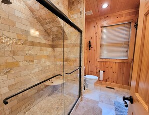 Ein Badezimmer mit einer Duschkabine aus Glas, einem Holzkosmetikschrank und einer Toilette.