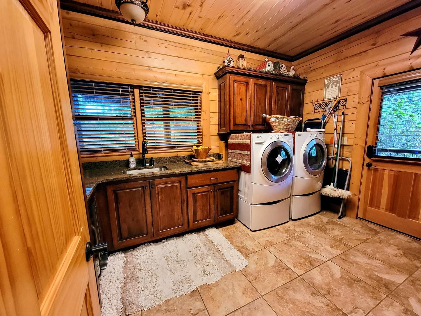 A compact laundry room with wooden cabinets, a washing machine, and a dryer.