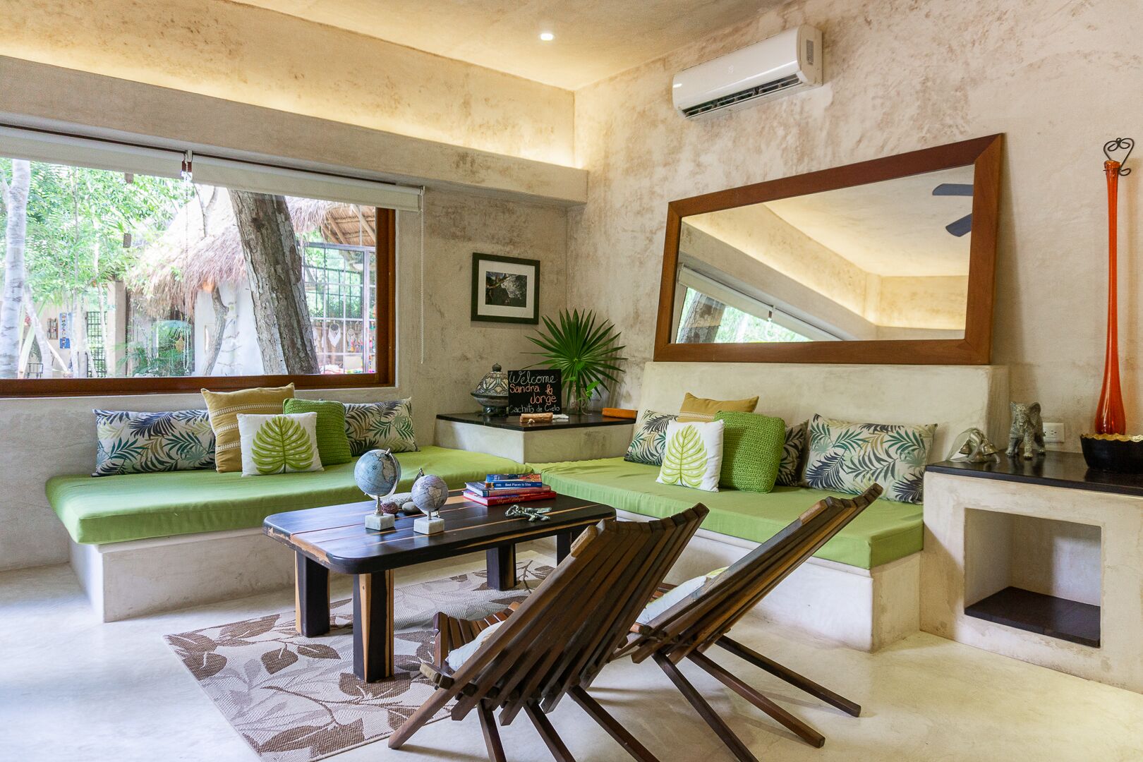 A cozy living room with a green sofa, a wooden coffee table, and a large mirror.