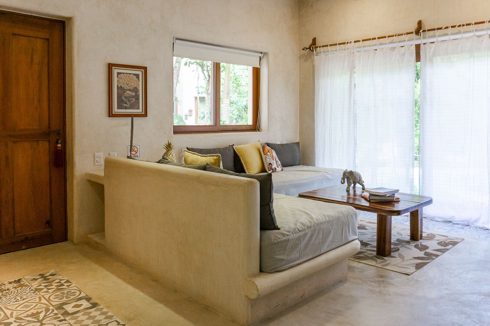 Una sala acogedora con un sofá, una mesita y una ventana con cortinas.