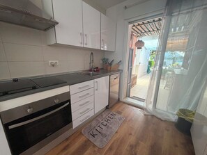 A modern kitchen with white cabinets, a stainless steel sink, and a built-in oven.
