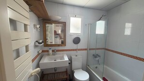Et badeværelse med toilet, vask og bruser.