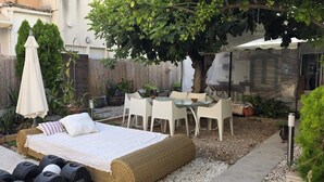 En hyggelig udendørs terrasse med seng, stole og bord.