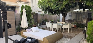 Un patio esterno accogliente con un letto, sedie e un tavolo.