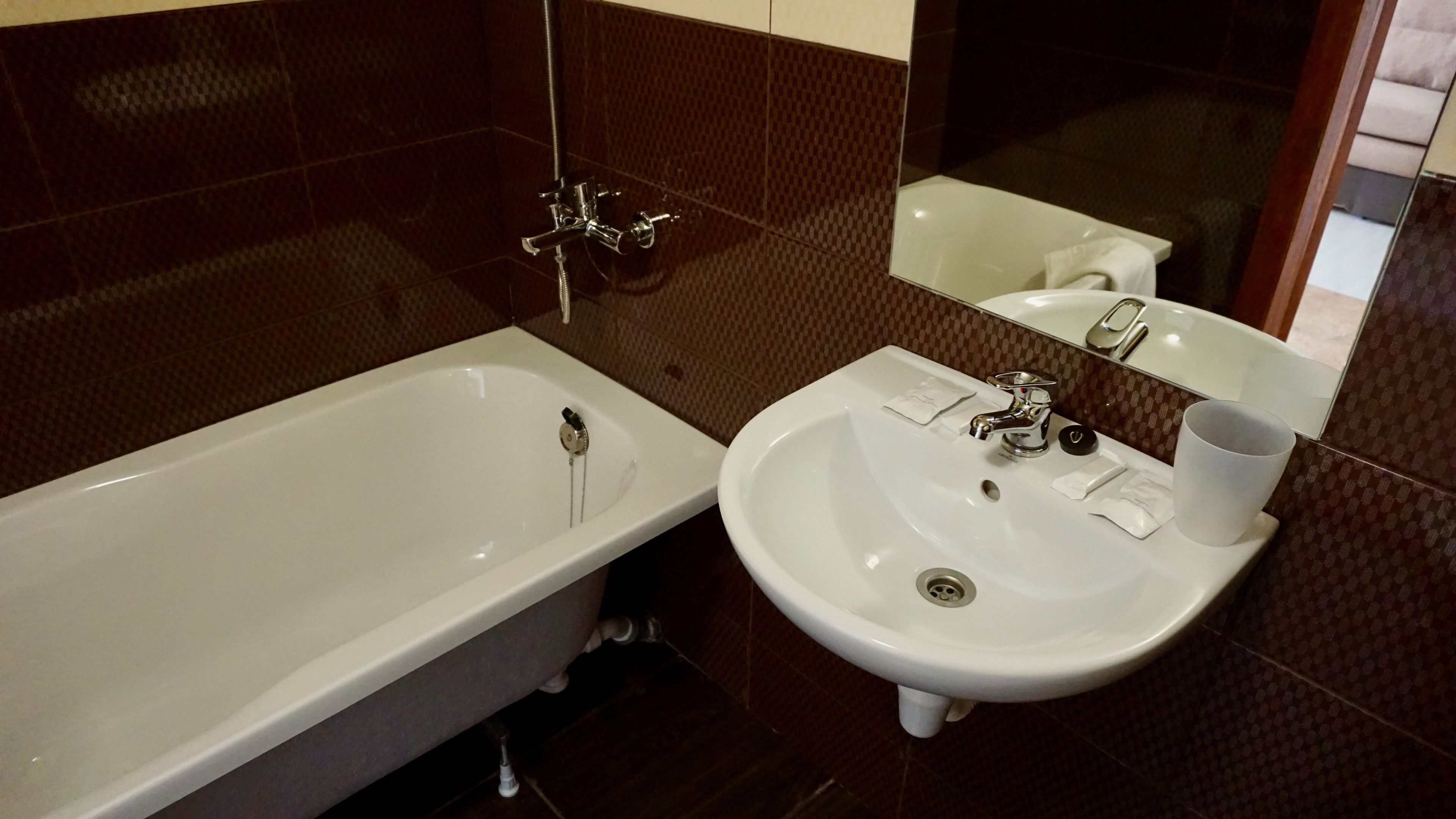 A bathroom with a bathtub, a sink, and a mirror.