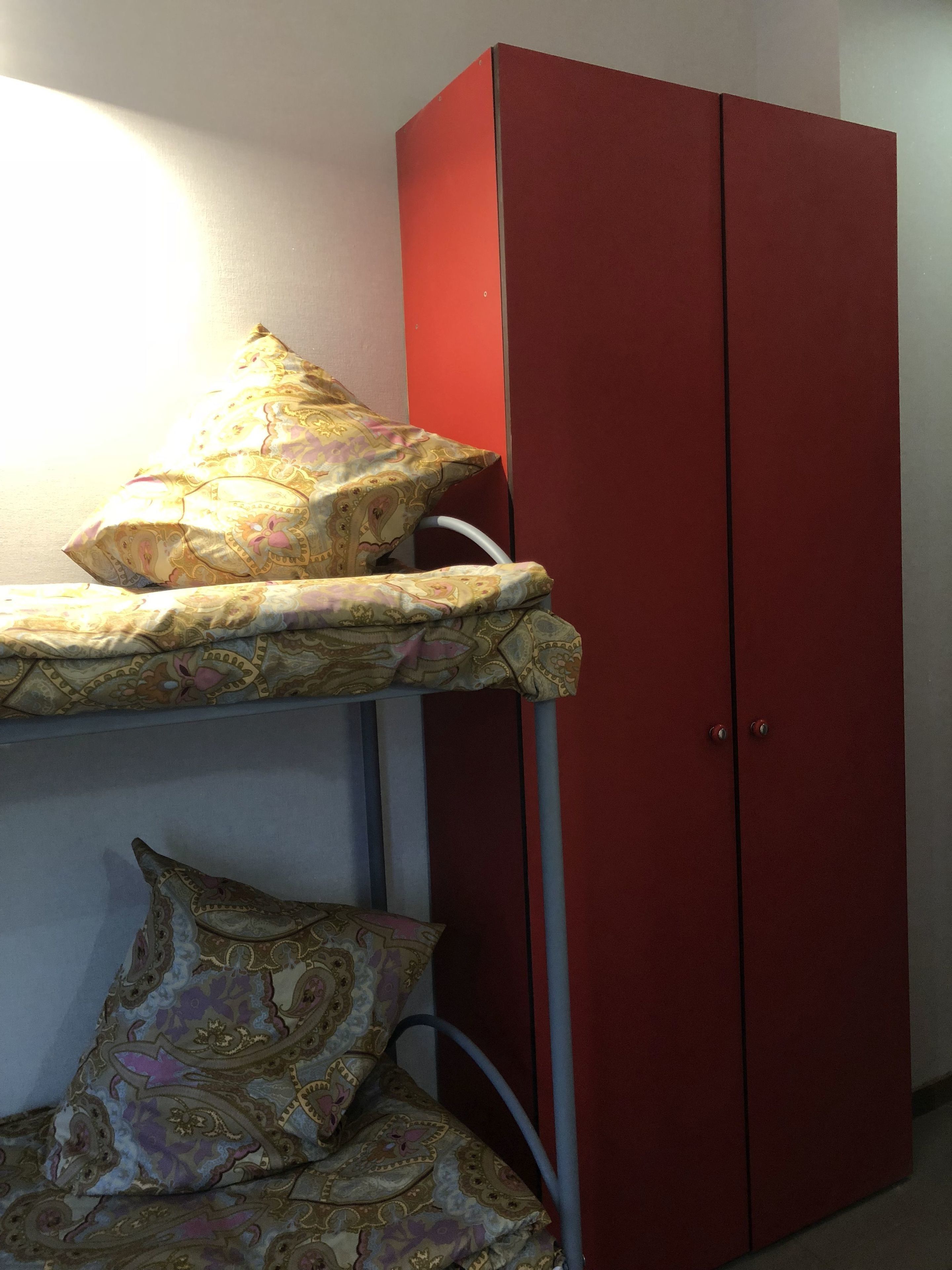 Una cama litera con ropa de cama estampada y un armario rojo.