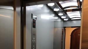 An elevator with a control panel, metallic walls, and a marble floor. - Hotel & Restaurant Zhuliany City (Sofiivska Borschahivka)