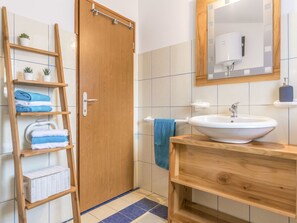 A bathroom with a wooden door, a white sink, a mirror, and a shelf with towels and a basket. - Wonderful private villa for 6 guests with A/C, WIFI, TV, terrace and pets allowed (Pazin)