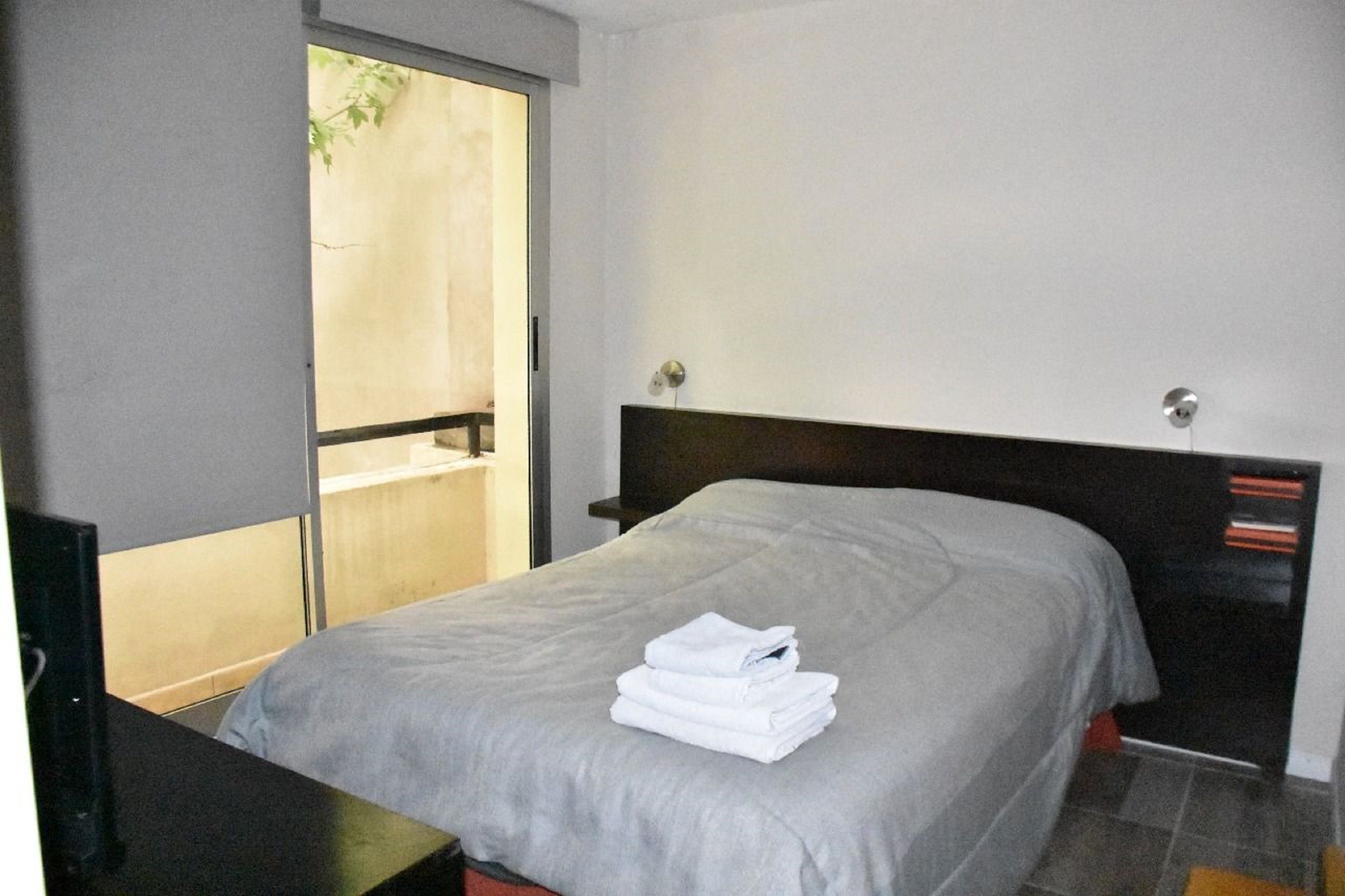 Une chambre d’hôtel avec un lit, une table de chevet, une fenêtre et une porte.