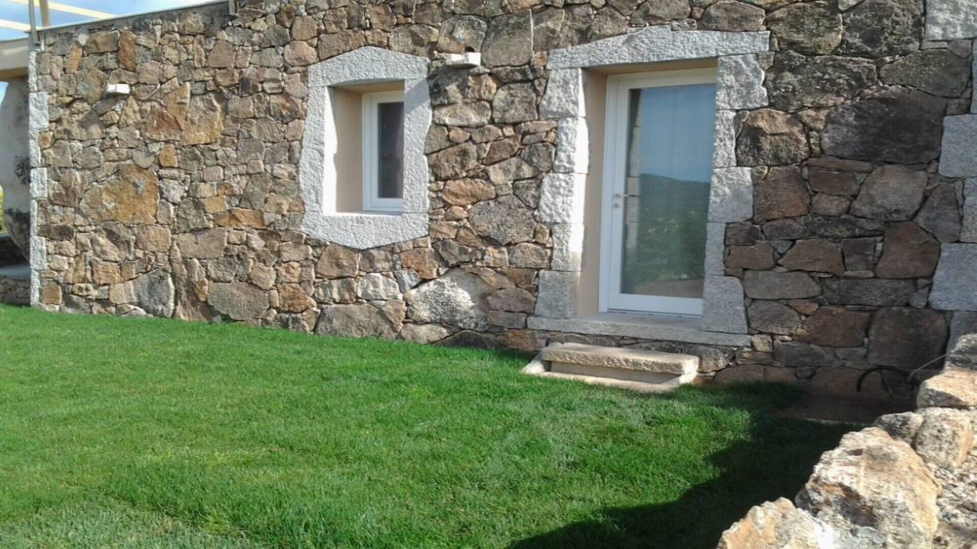 A stone building with two windows and a small porch.