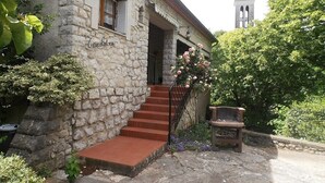 Ein Steingebäude mit einer Treppe, die zu einer Tür führt, einer Bank und einem Schild mit der Aufschrift 'GITE RURAL'.