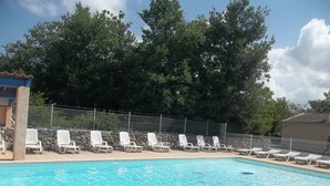 Ein Schwimmbecken mit weißen Liegestühlen und einer Steinmauer.